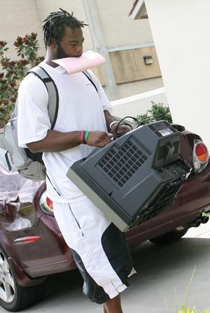 Junior linebacker Ali Highsmith carries a television into West Campus Apartments Sunday morning.