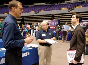 Michael Morgan, mechanical engineering junior (right), speaks to U.S. Air Force civilians Michael Clawson (left) and Jamie Cook (center) Thursday during the Federal Career Day in the Pete Maravich Assembly Center.