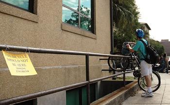 A student ignores the "No Bicycles" sign outside Allen Hall on Wednesday. The signs are meant to keep the adjacent wheelchair ramp free of obstacles.