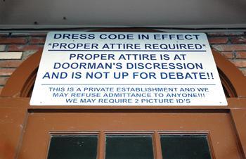 A sign hangs outside Reggie's bar informing patrons of dress code requirements in effect.