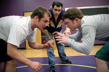 Joshua Kotter (left), education junior and Travis Olinde (right), general studies senior, prepare to wrestle Monday in the UREC. At center is their coach, mathematics graduate student Fareed Hawwa. They earned All-American honors this season.