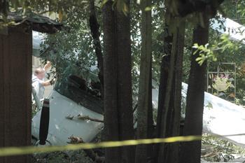 A man clears off the front of a plane that crash landed in the backyard of a house on Canonicus Street. No one was severely injured in the crash