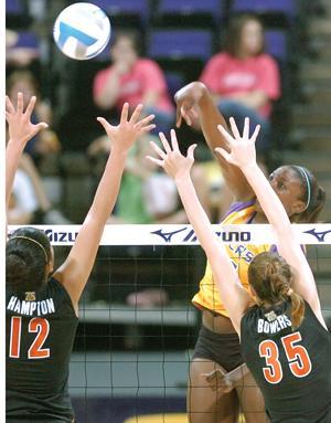 LSU sophomore Britnee Cooper spikes the ball over the outstretched hands of Florida players Marcie Hampton (12) and Kelsey Bowers (35) on Sunday in the PMAC.