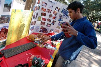 Rohithe Amarasinghe, mechanical engineering junior, arranges masks from Sri Lanka, whcih decorated an exhibition table at the Asia Expo in Free Speech Alley on Tuesday afternoon. The Asia Expo featured artifacts, photos, food, clothing and dance from the world's largest continent as part of a week-long celebration of world cultures.