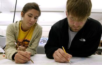 Marci Hamons and Robert Bass, landscape architecture seniors, sketch ideas for wildlife corridors on a landscape map of Point Coupee Parish in the Design Building Thursday evening. Bass said moving across a large map drawing out ideas that do not require high levels of detail is easier on paper than on a computer. After sketching out their ideas, Bass and Hamons will use Graphic Information System maps to make precise renderings of their designs to present to their clients for review.