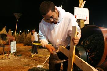 Ben Collier, general studies sophomore, hammers a wooden base onto a tree Tuesday evening at the Toy Soldier Christmas Trees lot on Perkins Road near Bluebonnet Boulevard.