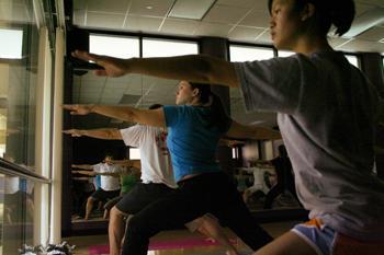 Michelle Tran (right), kinesiology sophomore, Beth Rugan, English graduate student, and others in the Gentle Yoga group exercise class stretch during their Tuesday evening class.