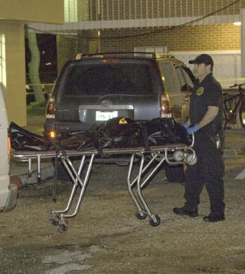 The body of one of the graduate students murdered on campus in December is carried to the coroner's van.