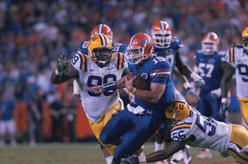 Junior quarterback Tim Tebow scrambles and is tackled by defensive tackle Marlon Favorite (99) and linebacker Perry Riley (56) during the game at Florida.