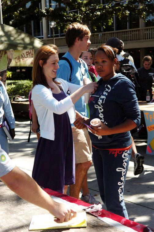 Mallory McGough (left), political science and communication studies senior and secretary of College Republicans, places a College Republicans sticker on Sabrina Parish (right), physics freshman, Wednesday afternoon in Free Speech Alley.