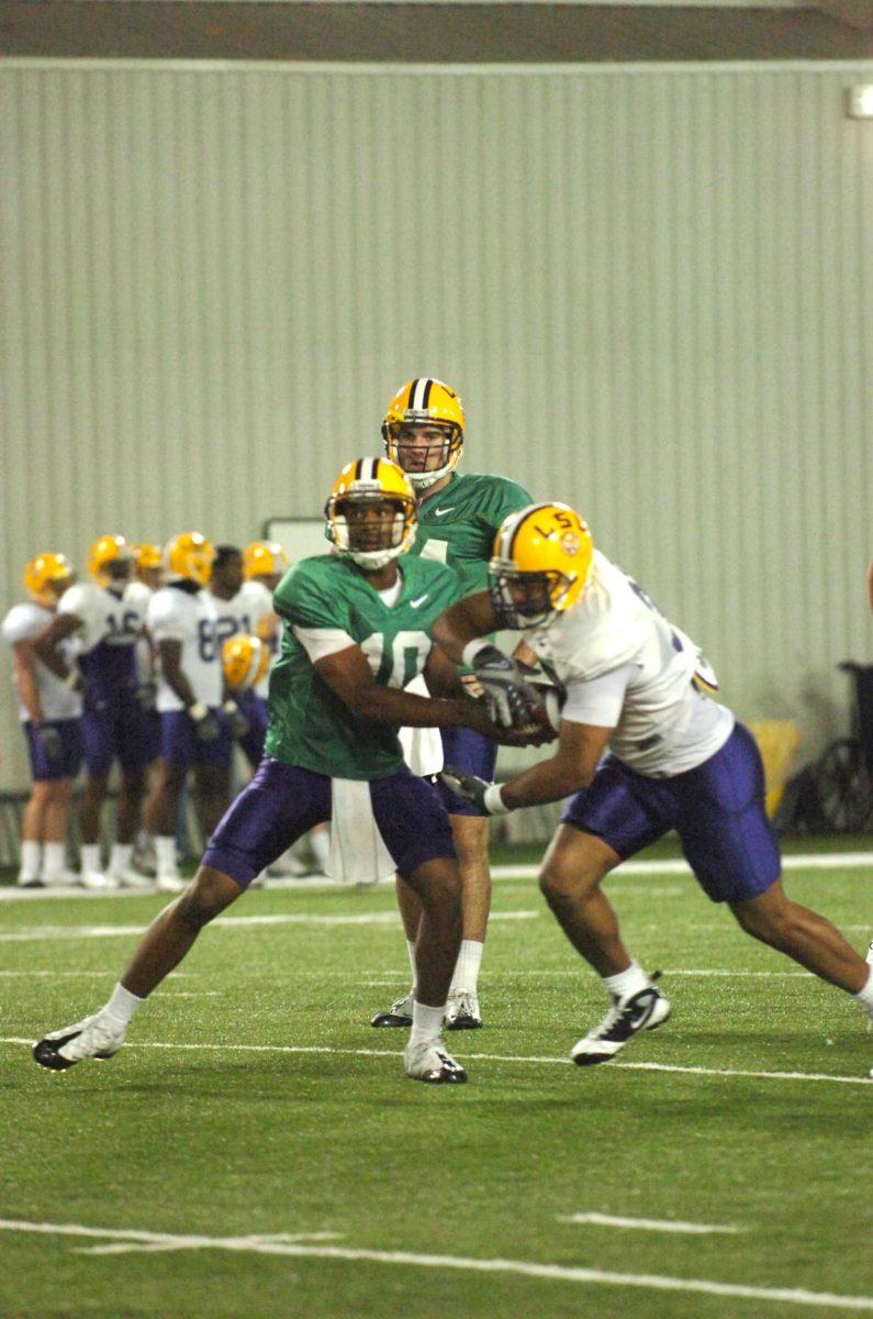 Senior running back Charles Scott (32) takes a handoff March 17 from freshman quarterback Russell Shepard (10) as freshman quarterback Chris Garrett (14) looks on.