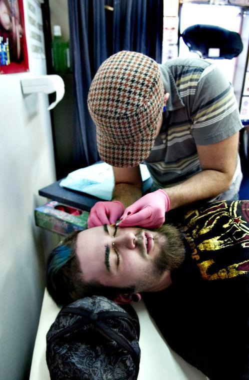 Piercer Jake Brooks puts dermal anchors in the face of a tattoo artist at Atomic Tattoo on March 15.