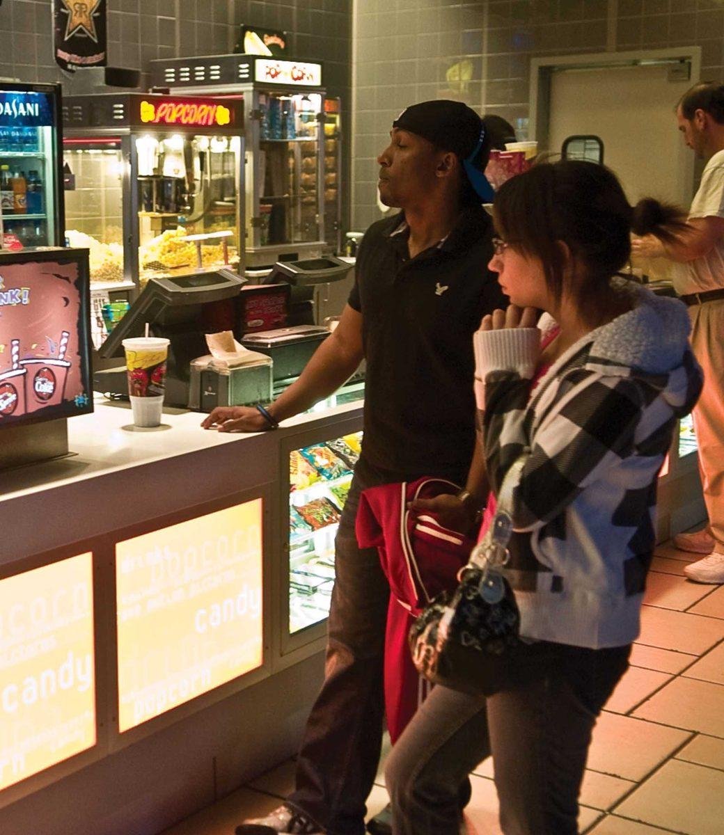 [Top] C.J. Hubert waits for his concessions inside the Rave Motion Pictures near the Mall of Louisiana. [Bottom] Anthony Granite and Megan Rose buy movie tickets Wednesday afternoon at the box office.