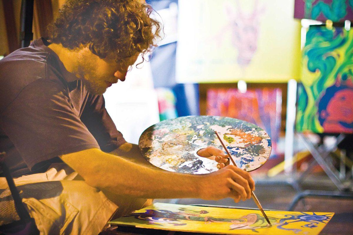 Chris Smith, studio art senior, works on a new painting during North Gate Fest. Louisiana cities are thriving as art markets for aspiring artists.