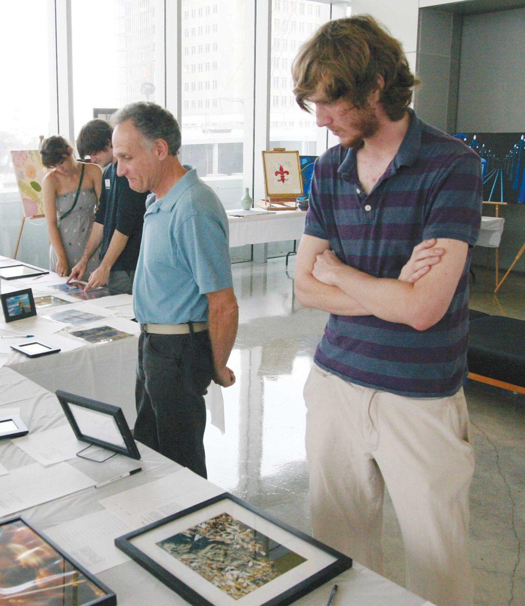 <p>Patrons survey art and place bids Tuesday evening during the Focus group’s Art Serving Art silent auction in the Shaw Center.</p>