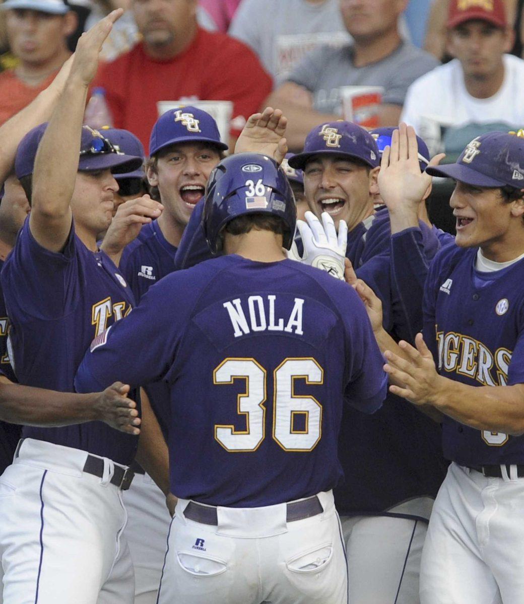 LSU freshman shortstop Austin Nola is mobbed by teammates after hitting a home run against Arkansas in the sixth inning of the Tigers' College World Series game in Omaha, Neb., on Monday.