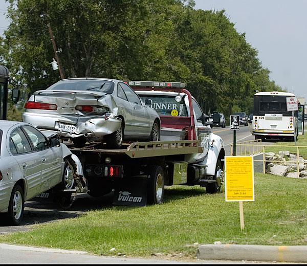 A tow truck removes cars from the side of Nicholson Drive. The cars were involved in an accident with a Tiger Trails bus.