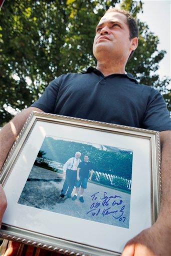 Simon Sousa, of Hyannis, Mass., holds a signed photograph of Sen. Edward Kennedy and himself near the Kennedy compound in Hyannisport, Mass., Wednesday, Aug. 26, 2009. Sousa says he was a house cleaner at the Kennedys over the last six years. Sen. Edward M. Kennedy who died late Tuesday after a yearlong struggle with brain cancer. He was 77.