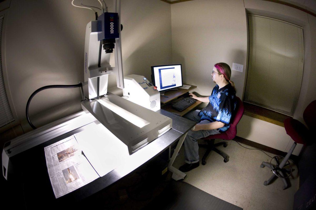 Gabe Harrell, digital services associate with LSU Libraries&#8217; Special Collections division, uses an overhead digital scanner to capture the image of a full-sized newsprint page. The project is a result of a two-year grant from the National Endowment for Humanities.