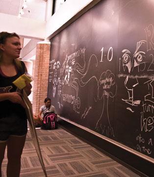 Maggie Boggs, interior design, painting and drawing junior examines the art wall Wednesday in the Design Building.