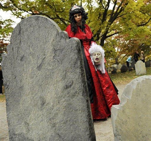 Lisa Moore, of Baltimore, Maryland, in costume, pauses to look at a tombstone as she walks through a cemetery in Salem, Mass, days before Halloween, Tuesday, Oct. 27, 2009.