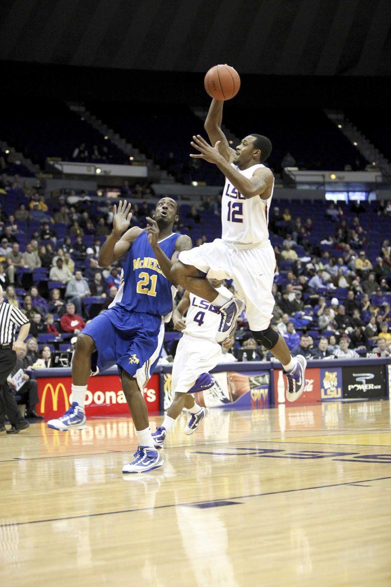 LSU freshman guard Aaron Dotson (12) jumps over McNeese State senior center Elbryan Neal (21) for a dunk Monday night during the Tigers' 83-60 win against the Cowboys in the PMAC.