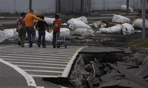 People walk aside a destroyed road in Talcahuano, Chile, Sunday, Feb. 28, 2010, following a devastatingearthquake that struck Chile early Saturday Feb. 27.