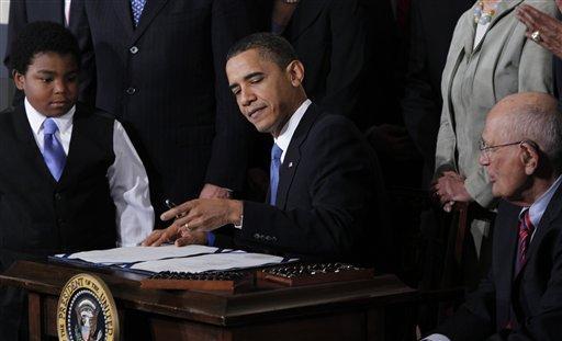 Marcelas Owens, 11, from Seattle, Wash., left, and Rep. John Dingell, D-Mich., right, look on as President Barack Obama signs the health&#160;care reform bill, Tuesday, March 23, 2010, in the East Room of the White House in Washington.