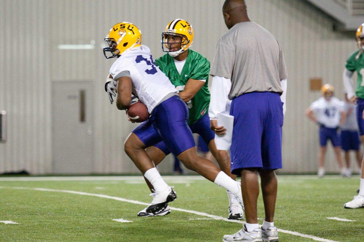 LSU junior quarterback Jordan Jefferson, center, hands the ball off to junior fullback Stevan Ridley during spring practice March 1, 2010, in the Indoor Practice Facility.