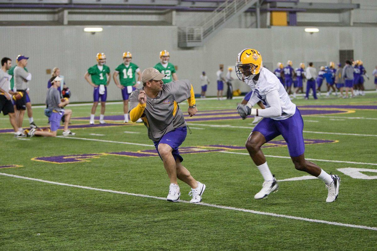 LSU wide receivers coach Billy Gonzales, left, runs with junior wide receiver Terrence Toliver during practice March 1 in the Indoor Practice Facility.