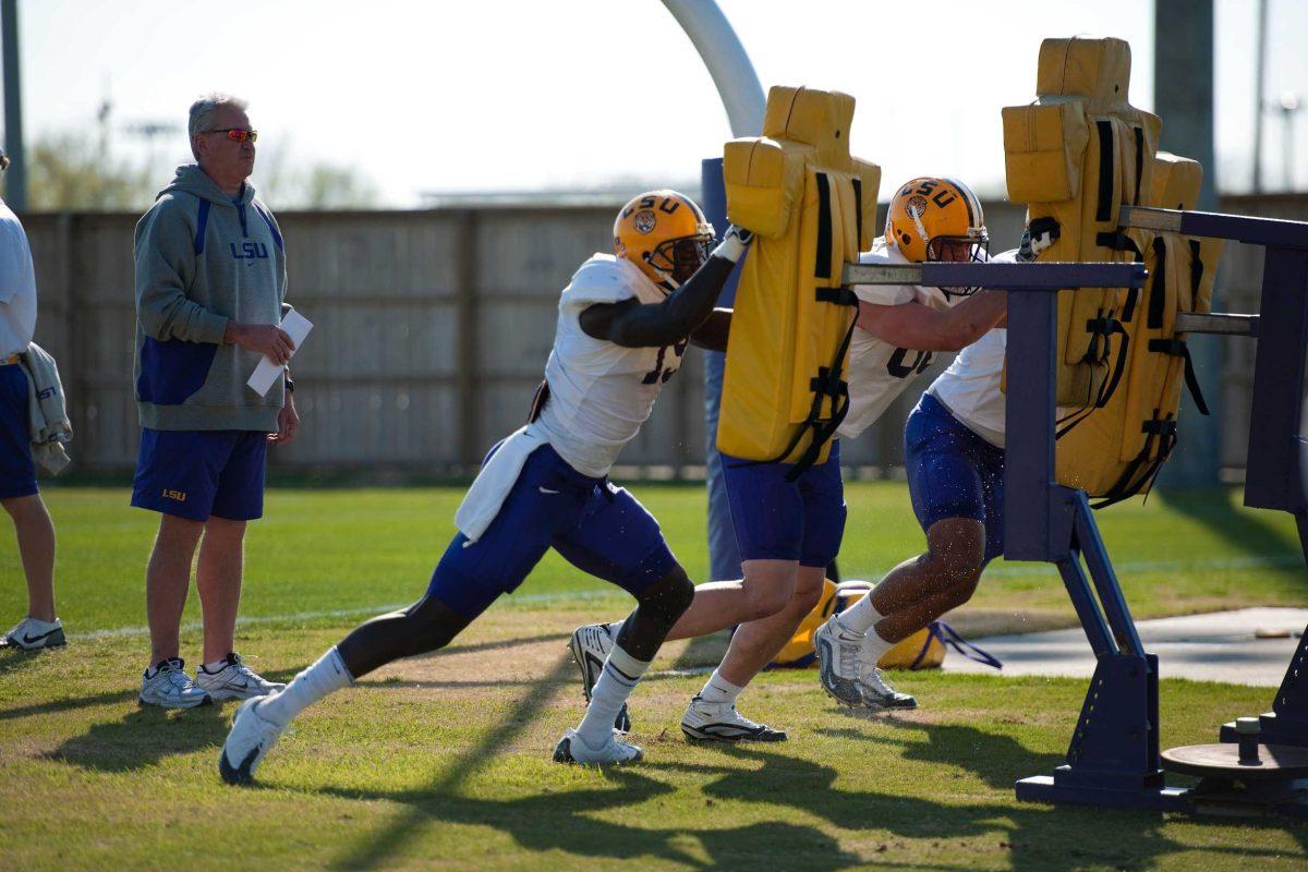 Steven Ensminger [tight ends coach], left, watches as the football players practice Monday afternoon at the Charles McClendon Practice Facility.