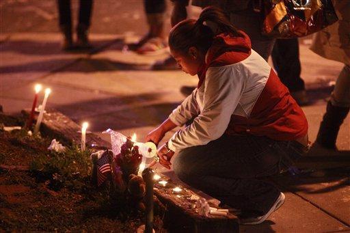 A woman attends a candlelight vigil for shooting victims in Washington, on Wednesday, March 31, 2010. A crowd, sprayed with bullets Tuesday night in a drive-by shooting that killed four and wounded five, had just returned from the funeral of man slain nearby and a 20-year-old is suspected in both shootings, authorities said Wednesday.