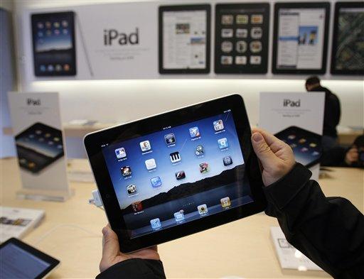 FILE - In this photo taken April 3, 2010, a customer uses an Apple iPad on the first day of Apple iPad sales at an Apple store in San Francisco. Although the advertised price for Apple Inc.'s least expensive iPad may be enticing to more than just the well-to-do geek elite, the actual cost of owning one quickly turns out to be much higher.