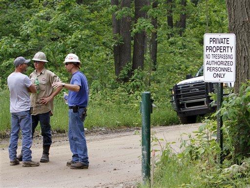 Workers talk as they block the road to a natural gas well that had gotten out of control the day before in Pennfield, Pa., Friday, June 4, 2010. The gas never caught fire and no injuries were reported, but state officials worried about an explosion before the well could be controlled. The well was brought under control just after noon Friday, about 16 hours after it started spewing gas and brine, said Elizabeth Ivers, a spokeswoman for driller EOG Resources Inc.