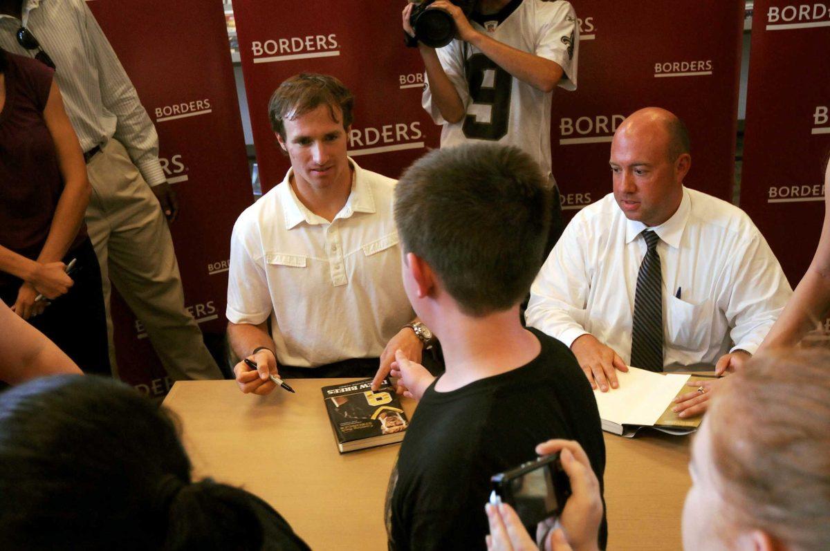 New Orleans Saints quarterback Drew Brees (left) signs books for customers Sunday at Borders bookstore at the Mall of Louisiana.