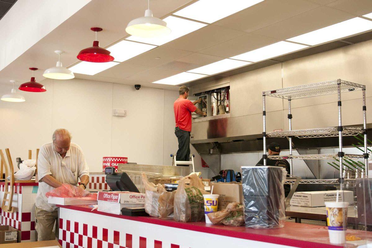 Construction workers finish installing kitchen components at Five Guys Burgers and Fries in Towne Center. The restaurant is scheduled to open Monday.