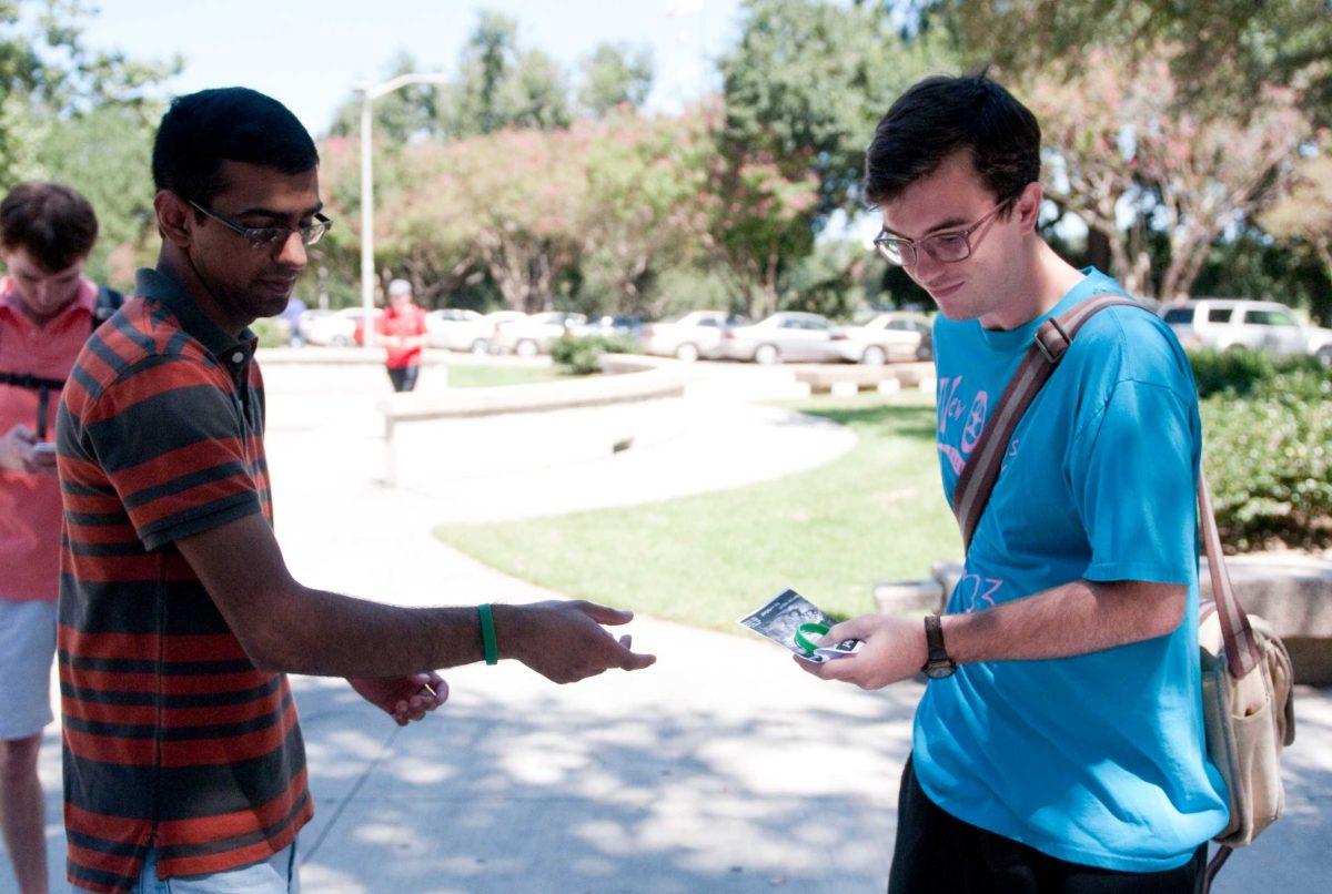 Religious studies senior Colin Ryan, right, buys a bracelet Monday from mass communication senior Sikandar Mehr during a fundraiser for Pakistani flood victims.