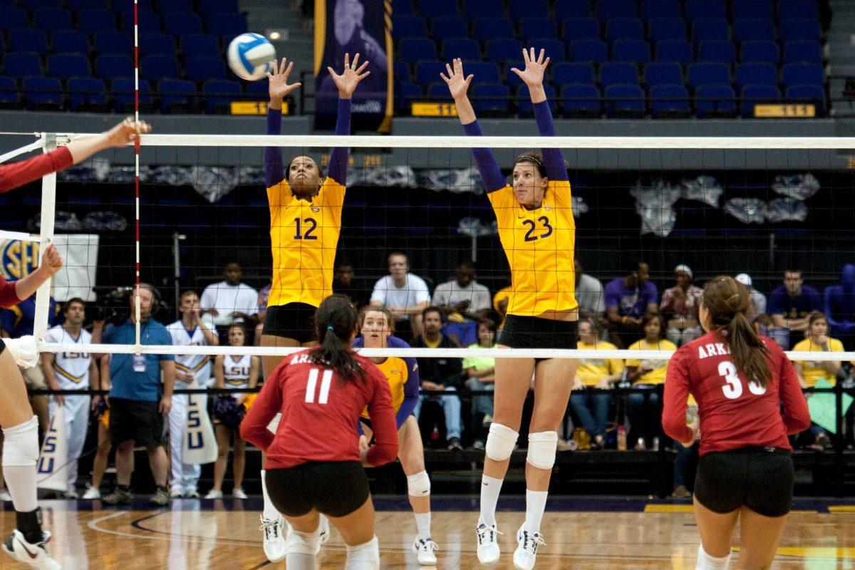 LSU senior setter Brittney Johnson (12) and junior middle blocker Michele Williams (23) jump to block a hit during the Tigers&#8217; 3-1 victory against Arkansas.