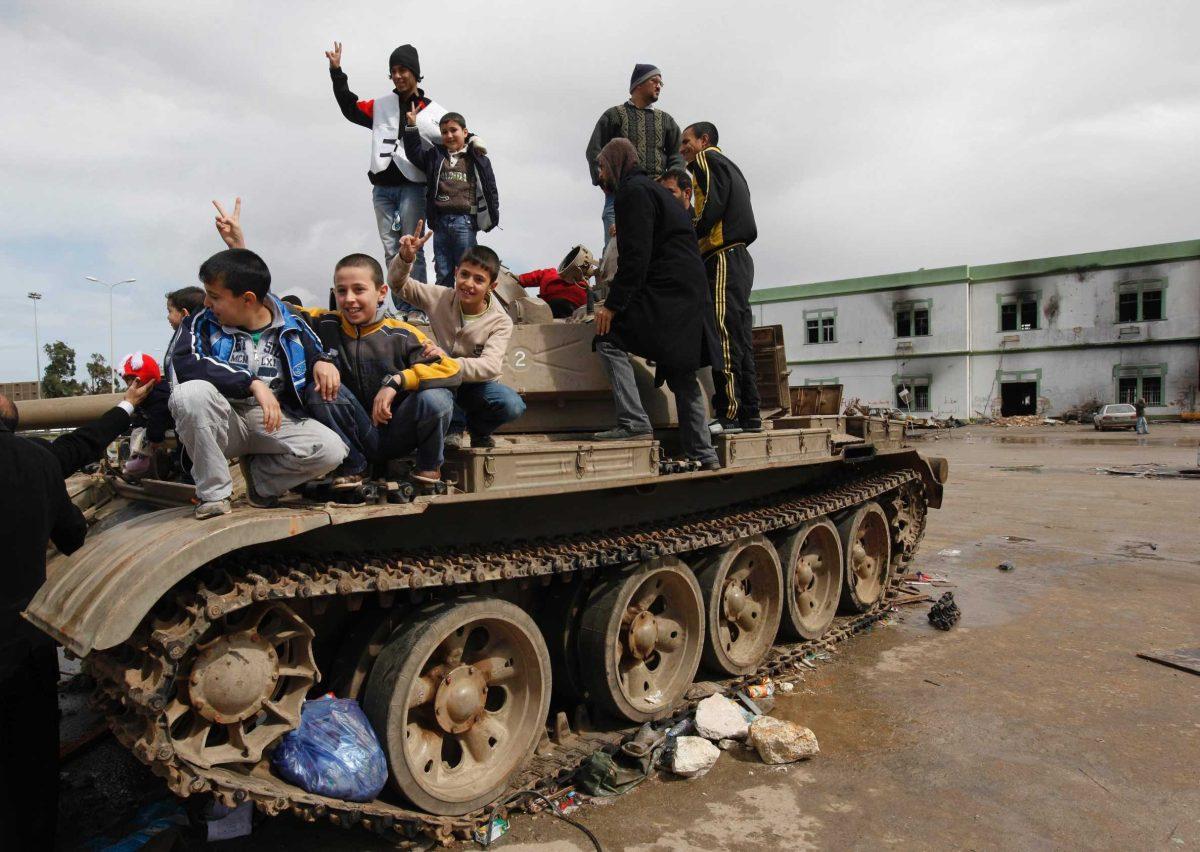 Libyan boys flash V signs Thursday as they stand over a destroyed cannon tank at Al-Katiba military base.