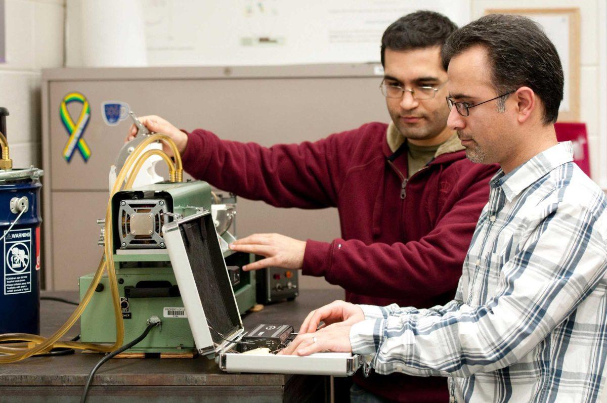 A Ph.D. student, left, and mechanical engineering professor Michael Khonsari monitor a machine used to predict the lifespans of materials.