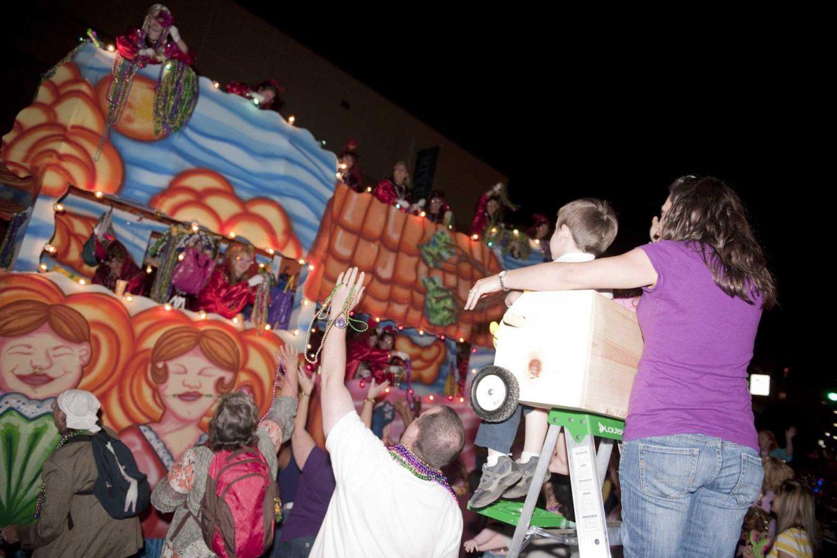 Parade-goers catch beads from a Krewe of Artemis float downtown Friday night.