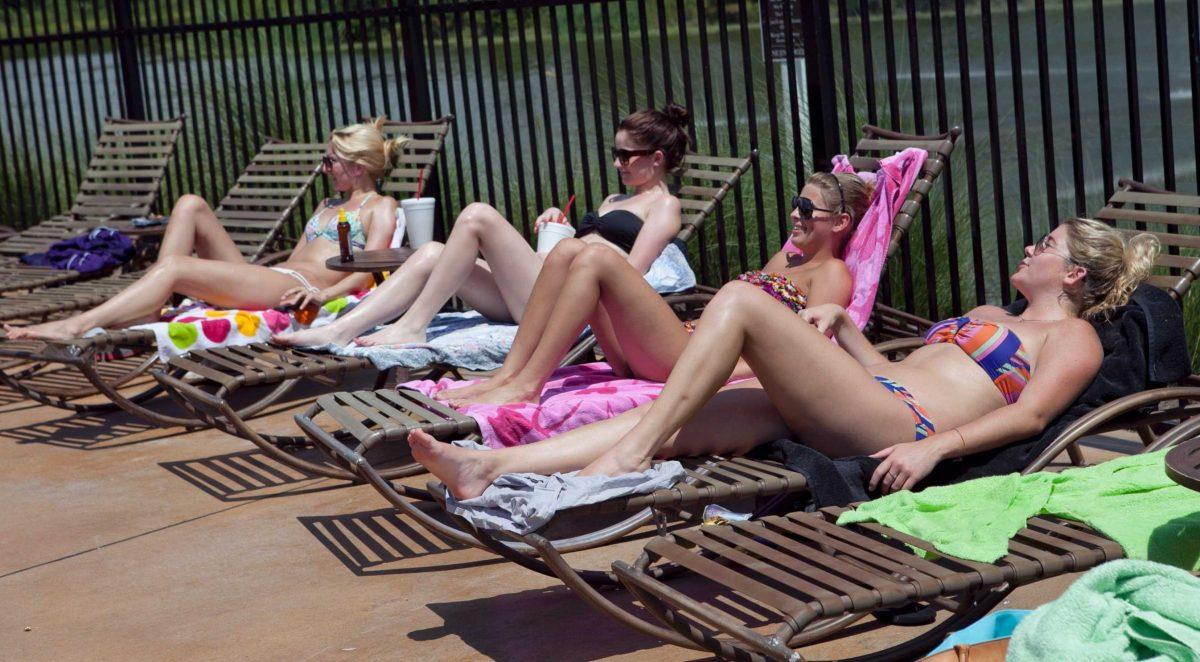 [From right] Kaitlin Sanford, interior design junior, Julia Sosa, international trade and finance junior, and Lauren Fonda, nursing alumna, lounge Monday by the Cottages&#8217; pool.