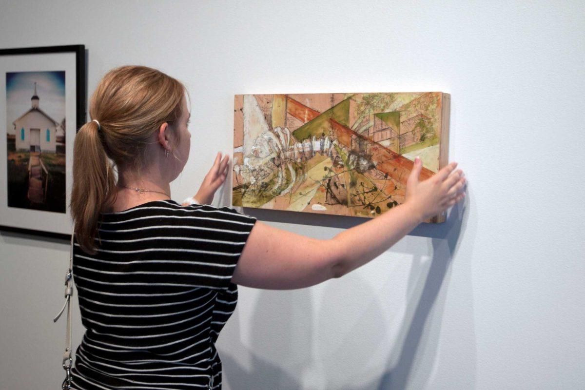 Sandy Parfait, community gallery curator for the Arts Council of Greater Baton Rouge, hangs artwork for Art Melt on Wednesday at the Louisiana State Museum.