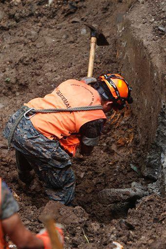 A soldier works to remove a body from the mud after a landslide caused by heavy rains in Boca Del Monte, Guatemala, Sunday Oct. 16, 2011. Guatemalan officials confirmed 28 deaths, adding that two more people were missing and that rain was expected for two more days. Guatemalan President Alvaro Colom declared a state of emergency that would be sent for approval to the congress Monday.