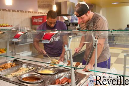 Freshmen football players Jarrett Fobbs (left) and Travis Dickson (right) dish up a hearty &#8220;Training Table&#8221; meal Wednesday at The 5 dining hall.