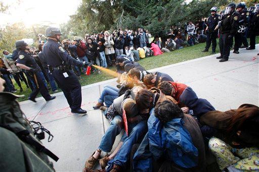 FILE - In this Nov. 18, 2011 file photo, University of California, Davis Police Lt. John Pike uses pepper spray to move Occupy UC Davis protesters while blocking their exit from the school's quad in Davis, Calif. Pike, the riot-clad police officer who pepper sprayed a row of peaceful Occupy Wall Street protesters at a California university last week, is a retired U.S. Marine sergeant twice honored for his police work on campus. (AP Photo/The Enterprise, Wayne Tilcock, File)