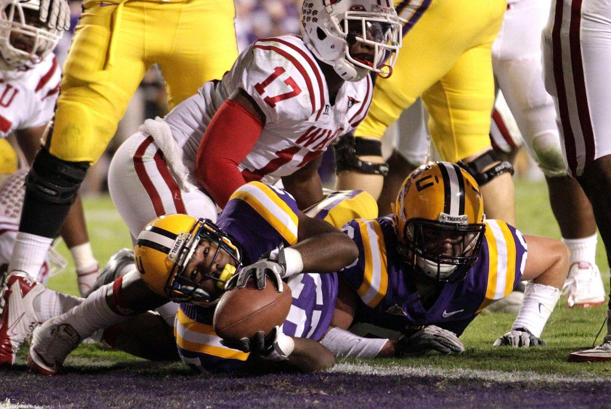 LSU running back Kenny Hilliard (27) scores a rushing touchdown past Western Kentucky linebacker C.J. Odom (17) during the second quarter of their NCAA college football game in Baton Rouge, La., Saturday, Nov. 12, 2011. (AP Photo/Gerald Herbert)