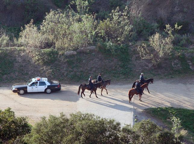 Mounted Los Angeles Police officers search the Bronson Canyon area of Griffith Park after a human head was discovered Tuesday by two people walking their dogs below the Hollywood Sign in Los Angeles, Wednesday, Jan. 18, 2012. Investigators have also two severed hands.