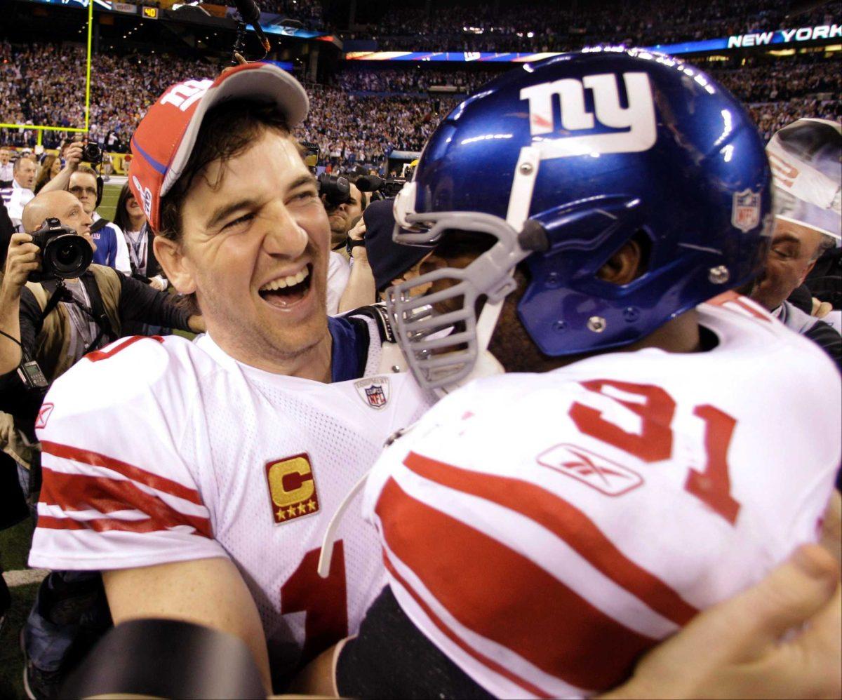 New York Giants quarterback Eli Manning (left) and teammate Justin Tuck (right) celebrate Sunday after their team&#8217;s 21-17 win against the New England Patriots in Super Bowl XLVI in Indianapolis.