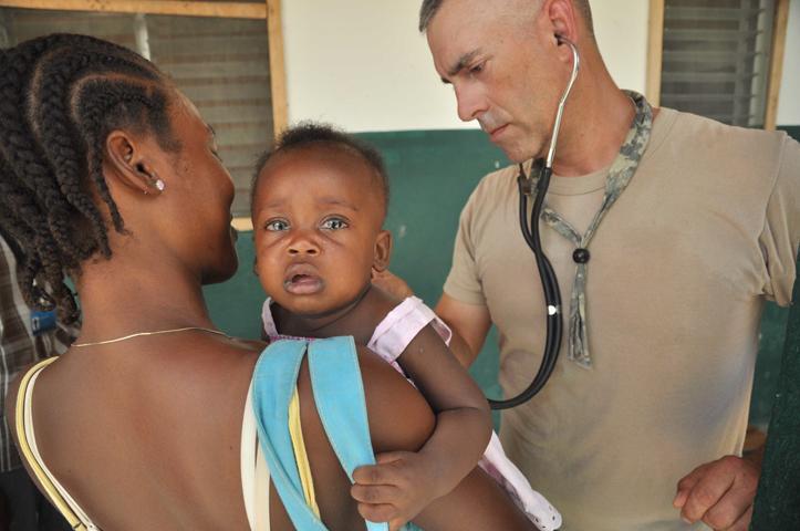 Major Greg Pieper [right], a nurse practitioner for the medical readiness training exercise, screens a young patient June 14, 2011, as her mother comforts her.